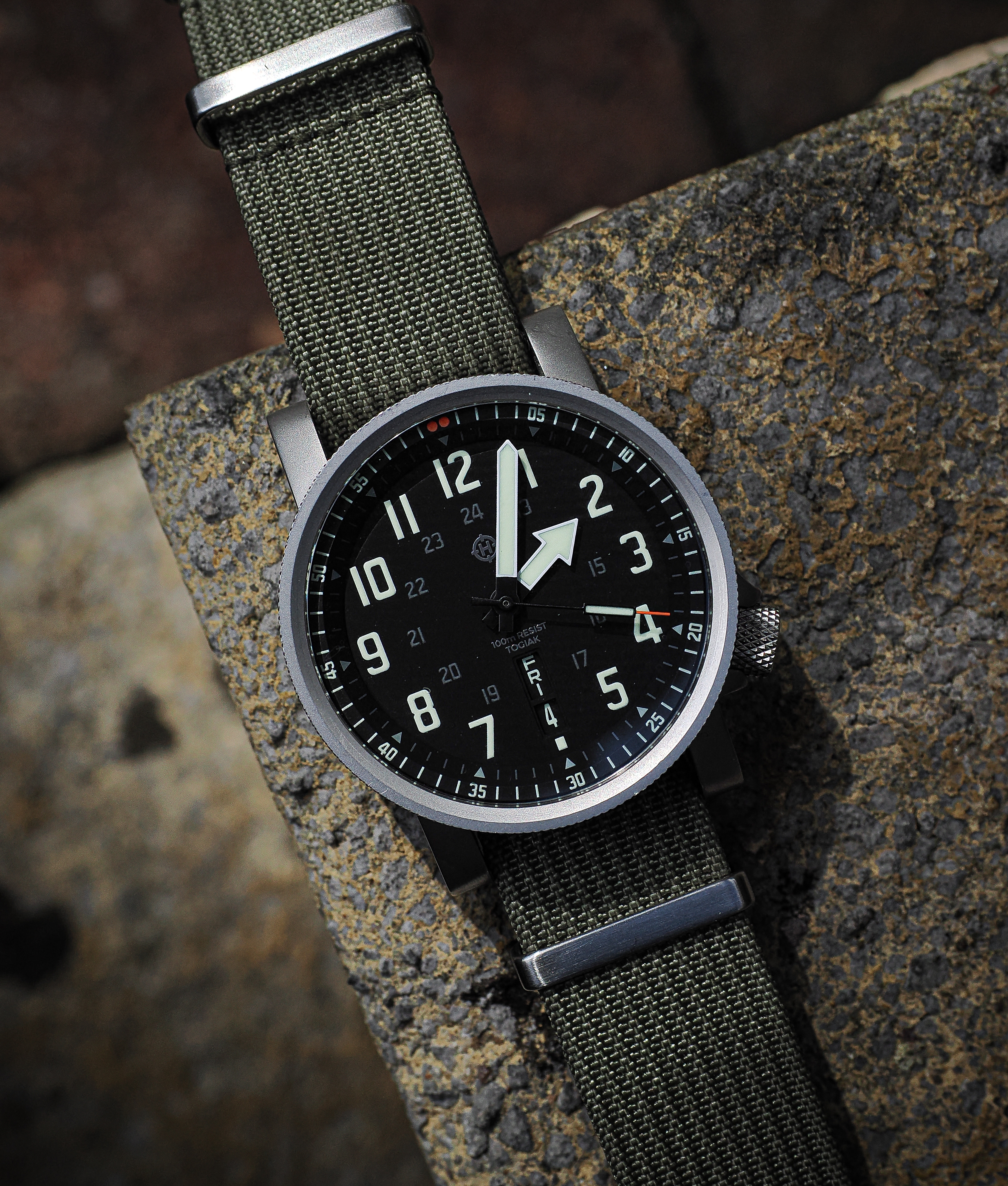 HELM Togiak Scout field watch photographed outdoors against textured stone