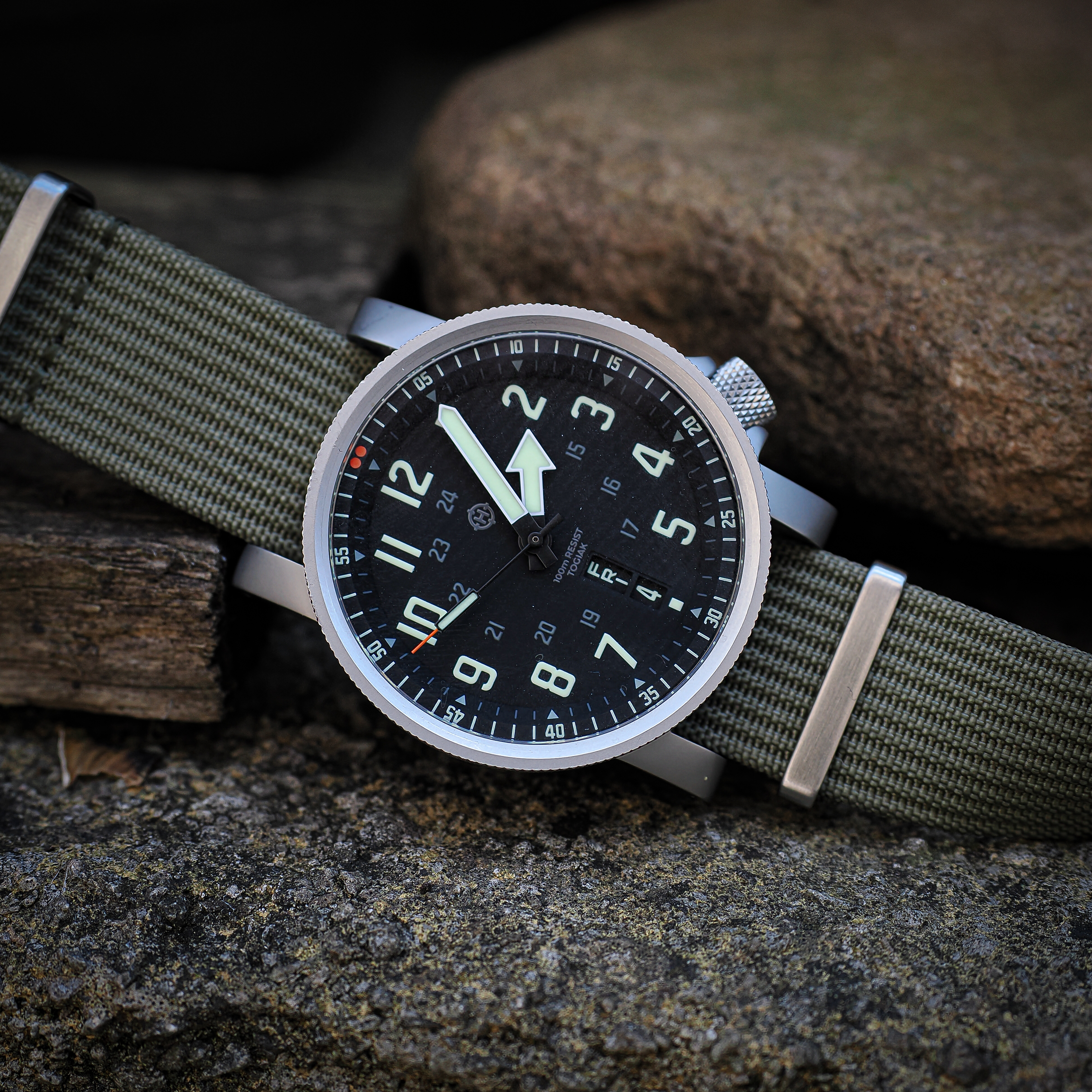 HELM Togiak Scout photographed outdoors on weathered stone with olive nylon strap
